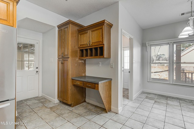 kitchen with decorative light fixtures, light tile patterned flooring, a textured ceiling, and stainless steel refrigerator