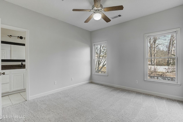 carpeted empty room with ceiling fan, plenty of natural light, and sink