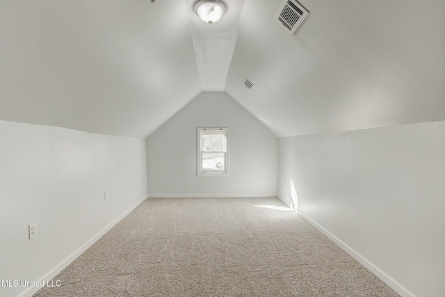 additional living space featuring light colored carpet and vaulted ceiling