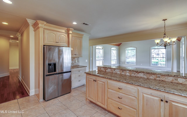 kitchen with light tile patterned floors, ornamental molding, stainless steel fridge with ice dispenser, and light stone counters