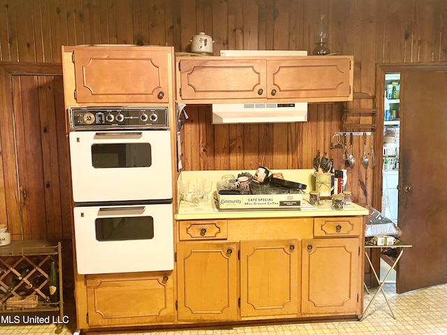 613 Georgetown St, Hazlehurst, MS 39083 - kitchen featuring white double oven, wood walls, under cabinet range hood, and light countertops
