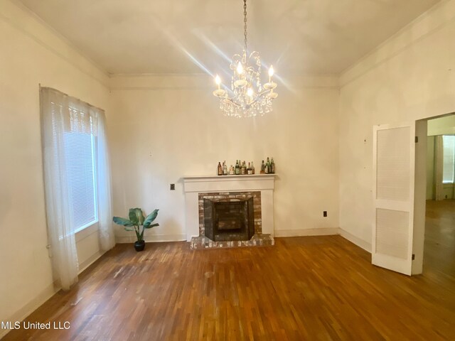 613 Georgetown St, Hazlehurst, MS 39083 - unfurnished living room with wood finished floors, a chandelier, a fireplace with raised hearth, baseboards, and ornamental molding