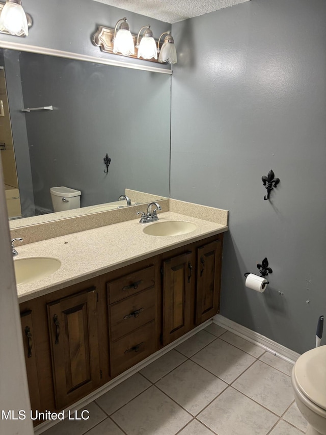 bathroom with a textured ceiling, toilet, vanity, and tile patterned flooring