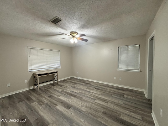 empty room with ceiling fan, dark wood-type flooring, and a textured ceiling