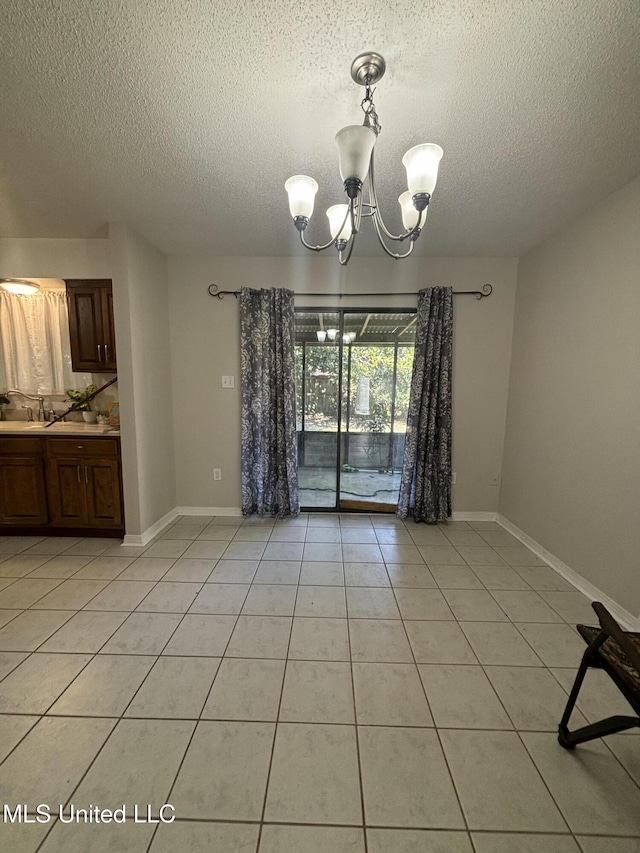 unfurnished dining area featuring sink, a textured ceiling, light tile patterned floors, and a chandelier