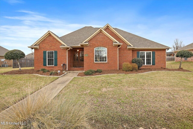 ranch-style house featuring brick siding, fence, and a front yard