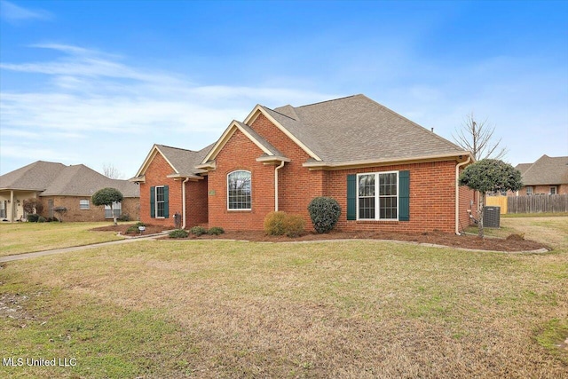 view of front of property with fence, a front lawn, cooling unit, and brick siding