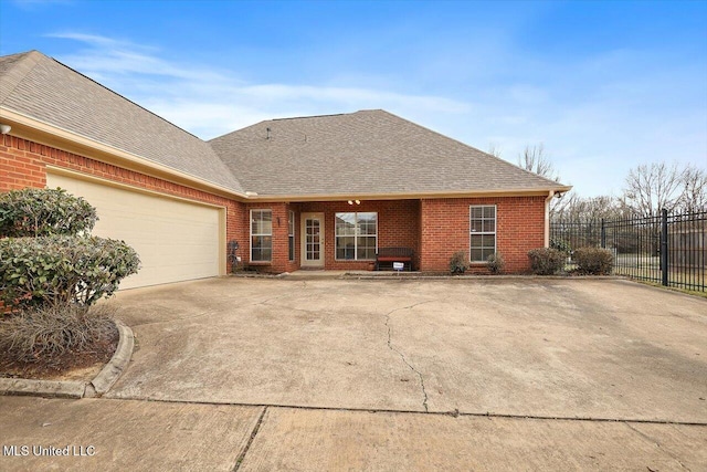 view of front of home with a garage, driveway, roof with shingles, fence, and brick siding