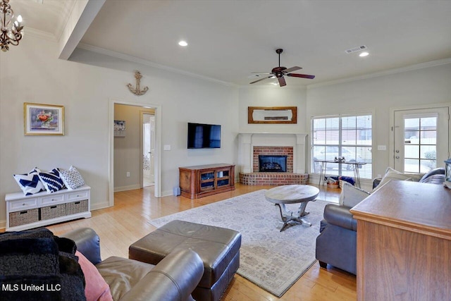 living area featuring ceiling fan, recessed lighting, light wood-style floors, ornamental molding, and a brick fireplace