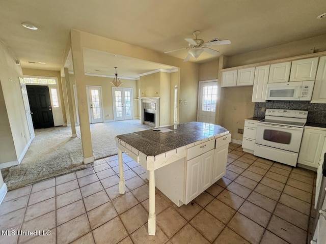 kitchen featuring white appliances, ceiling fan, tasteful backsplash, a kitchen bar, and light carpet