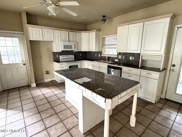 kitchen with white cabinetry, white appliances, sink, and a breakfast bar area