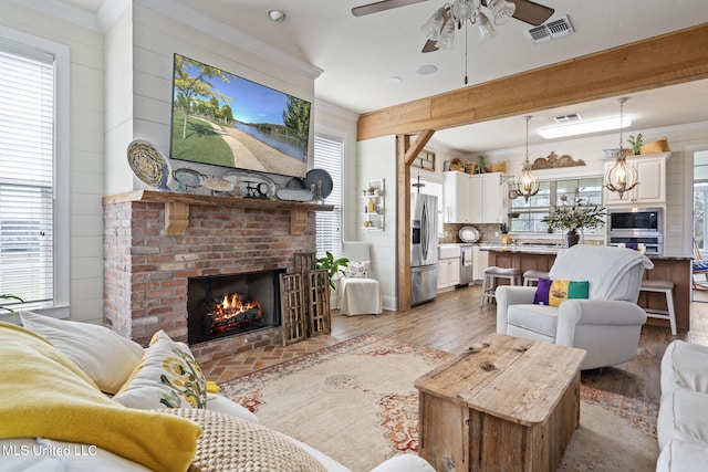 living area with ornamental molding, a wealth of natural light, and visible vents