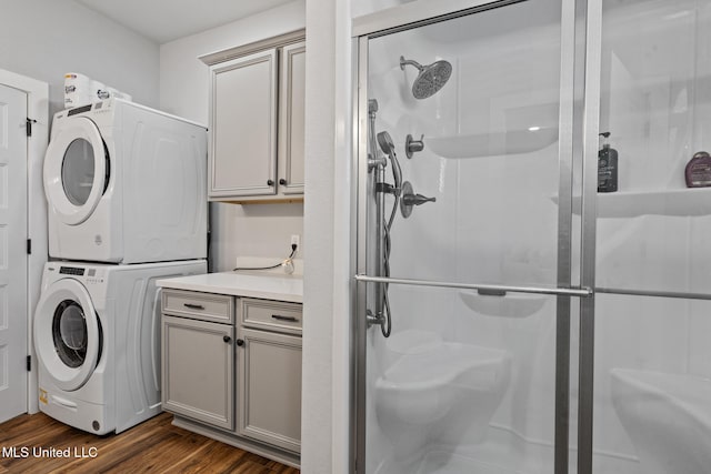 clothes washing area with laundry area, dark wood finished floors, and stacked washing maching and dryer