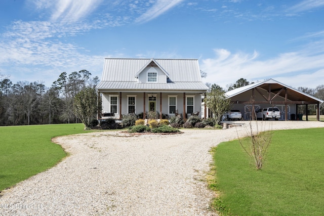 view of front of house featuring gravel driveway, covered porch, metal roof, and a front lawn