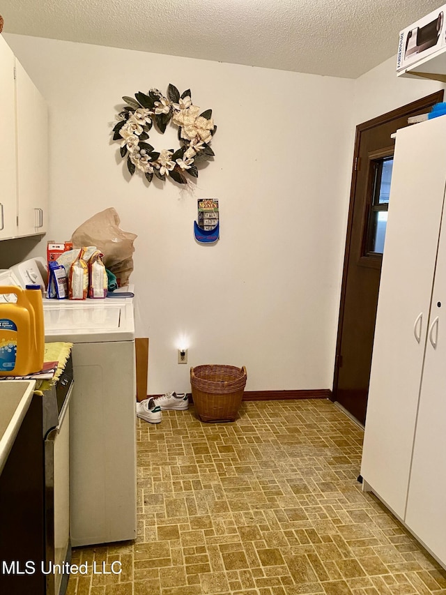 laundry room with cabinets and a textured ceiling