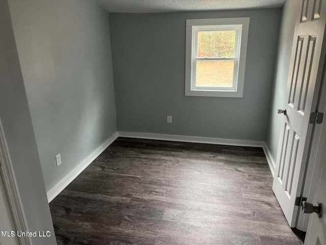 spare room with a textured ceiling and dark hardwood / wood-style flooring