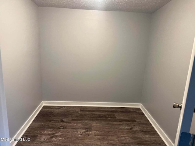 unfurnished room featuring a textured ceiling and dark hardwood / wood-style flooring