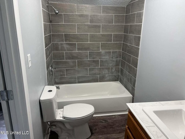 full bathroom with hardwood / wood-style flooring, toilet, tiled shower / bath combo, vanity, and a textured ceiling