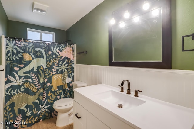bathroom featuring wainscoting, toilet, wood finished floors, vanity, and a shower with shower curtain
