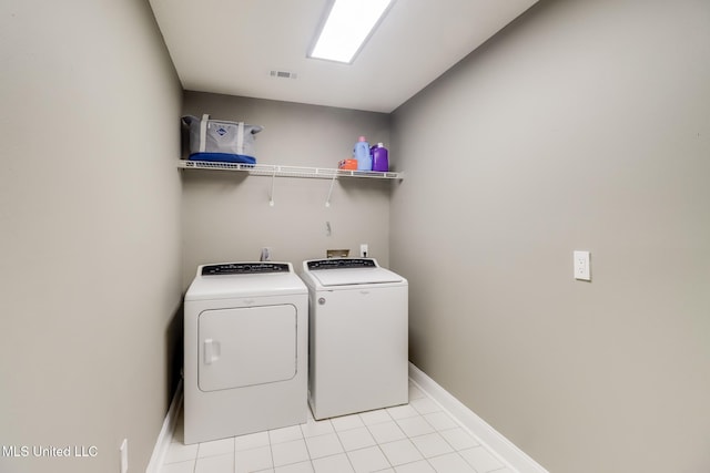 laundry area with washer and clothes dryer, light tile patterned flooring, and baseboards