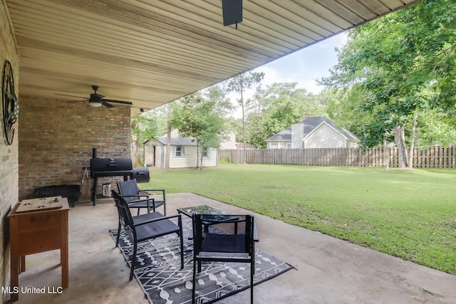view of patio / terrace with a ceiling fan, a storage unit, an outdoor structure, and grilling area