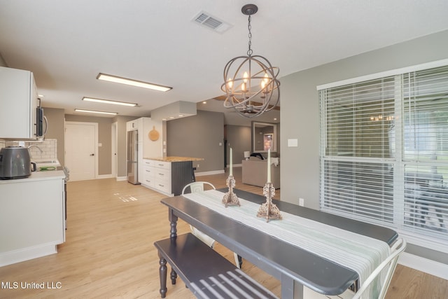dining space with baseboards, a chandelier, and light wood-style flooring
