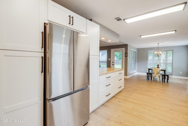 kitchen featuring freestanding refrigerator, light wood-style floors, white cabinetry, and a chandelier
