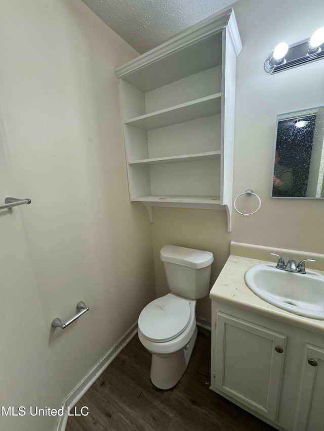 bathroom featuring wood-type flooring, toilet, a textured ceiling, and vanity