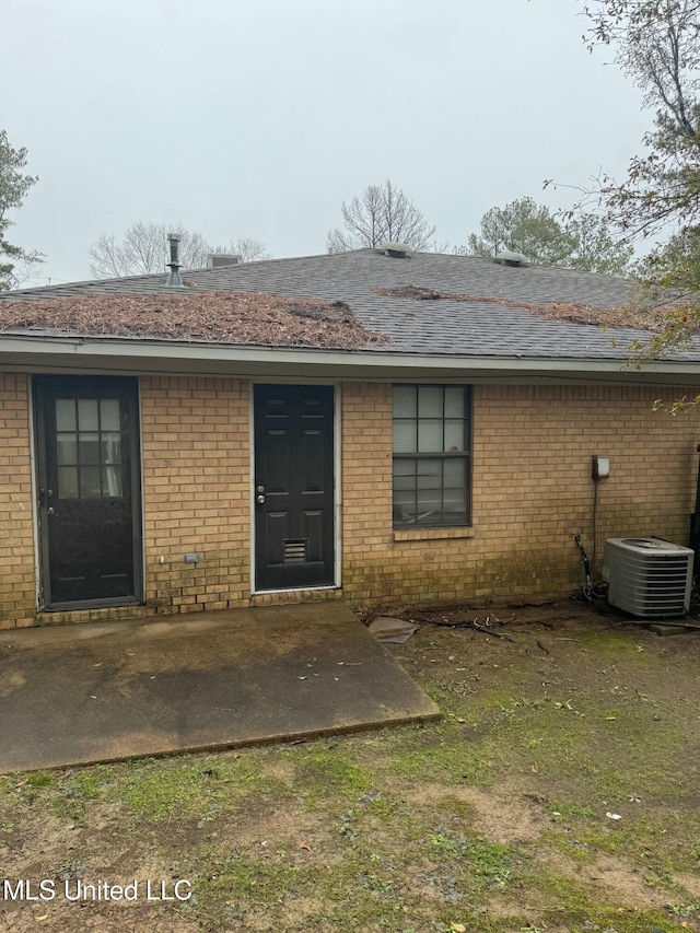 view of exterior entry with central AC and a patio area