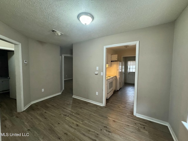 spare room featuring dark hardwood / wood-style floors and a textured ceiling