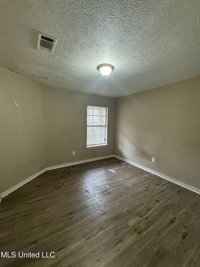 spare room with a textured ceiling and dark hardwood / wood-style flooring