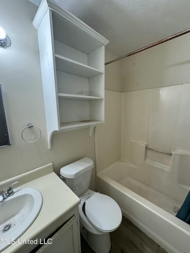 full bathroom featuring wood-type flooring, bathtub / shower combination, vanity, toilet, and a textured ceiling