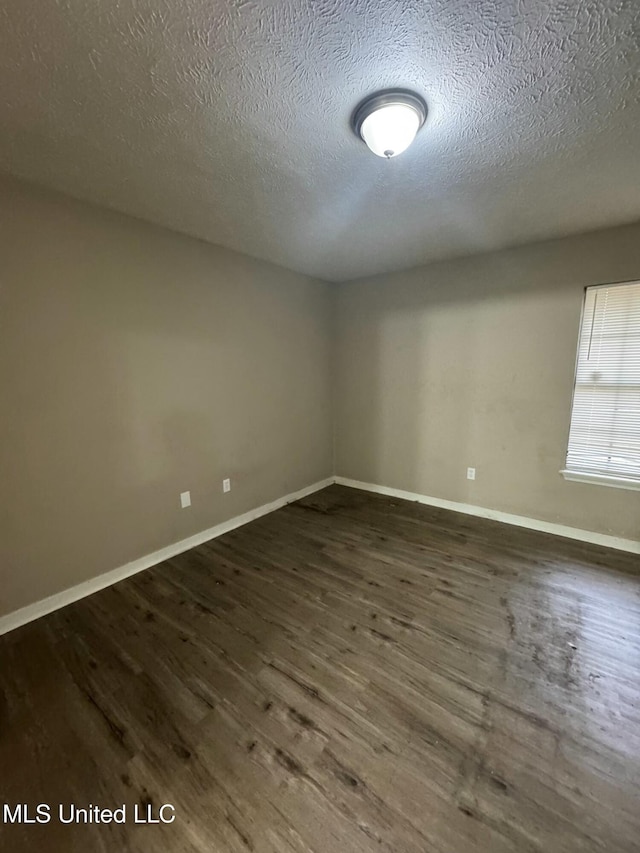 empty room with dark wood-type flooring and a textured ceiling