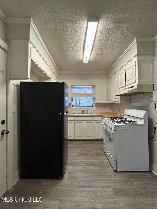 kitchen with white cabinetry, sink, black fridge, white gas stove, and light hardwood / wood-style flooring