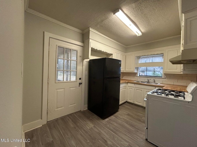 kitchen with crown molding, black refrigerator, white cabinets, dark hardwood / wood-style flooring, and white gas range