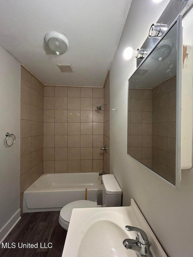 full bathroom with sink, tiled shower / bath combo, hardwood / wood-style floors, and toilet