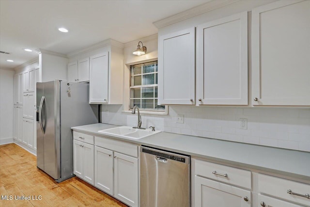 102 Holly Trl, Brandon, MS 39047 - kitchen featuring appliances with stainless steel finishes, a sink, tasteful backsplash, white cabinetry, and light wood finished floors