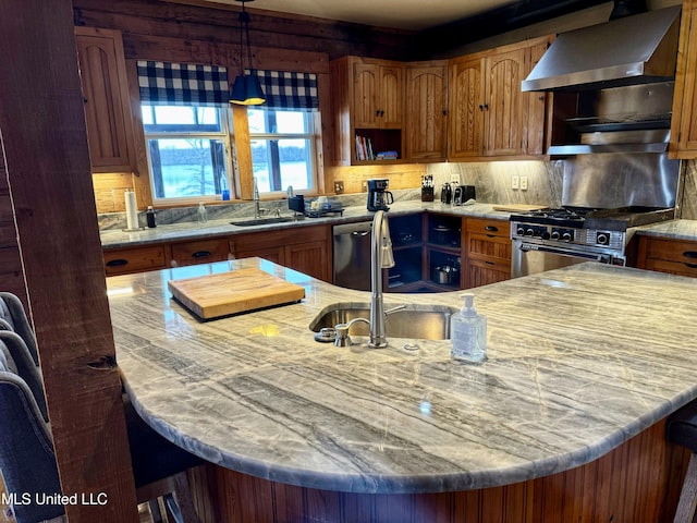 kitchen featuring sink, hanging light fixtures, wall chimney range hood, stainless steel appliances, and backsplash