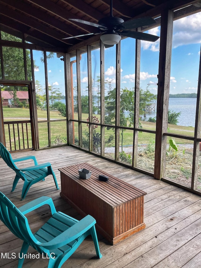 sunroom with ceiling fan and a water view