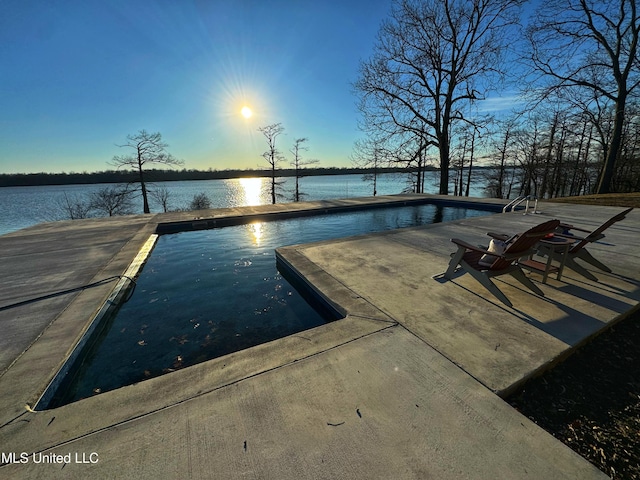 pool at dusk featuring a water view