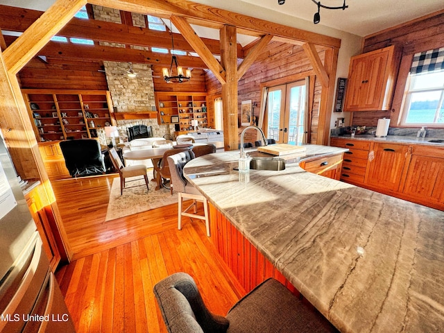 kitchen with french doors, sink, decorative light fixtures, light hardwood / wood-style flooring, and a notable chandelier