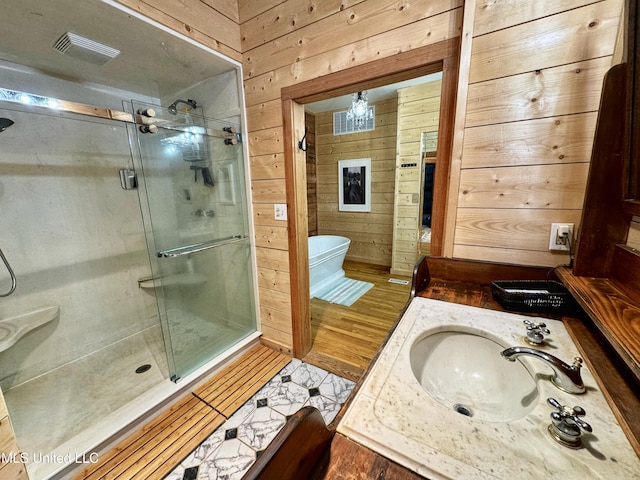 bathroom with an enclosed shower, vanity, and wooden walls