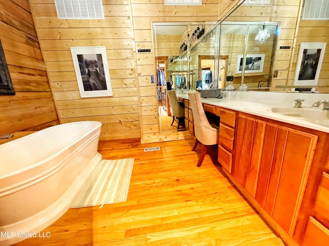 bathroom with hardwood / wood-style flooring, vanity, a bath, and wooden walls