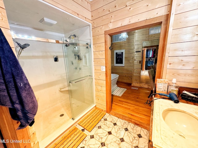 bathroom with walk in shower, vanity, wooden walls, and toilet