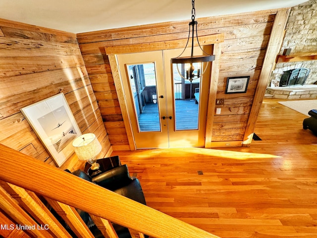 interior space with hardwood / wood-style floors, wooden walls, and french doors