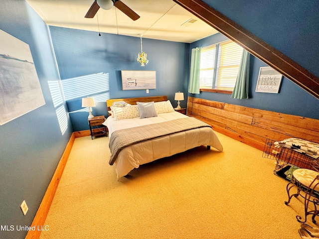 carpeted bedroom featuring ceiling fan and wooden walls