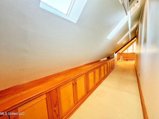 hallway with vaulted ceiling with skylight and light carpet