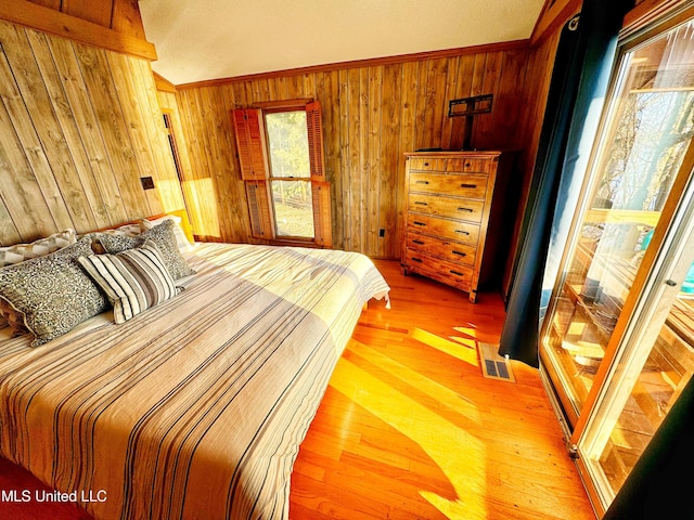 bedroom with hardwood / wood-style flooring, ornamental molding, and wood walls