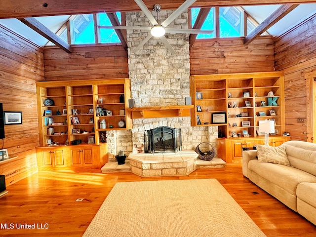 living room with a fireplace, wooden walls, a skylight, and hardwood / wood-style floors