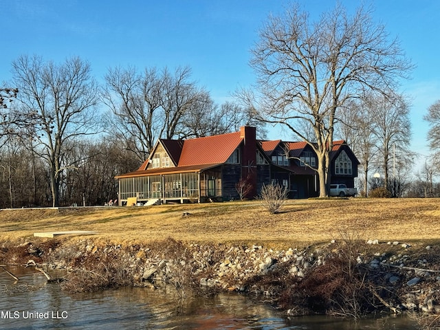 back of house featuring a sunroom and a water view